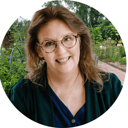 round headshot of Debby Ward, organic garden coach, speaker , instructor and writer in front of a garden